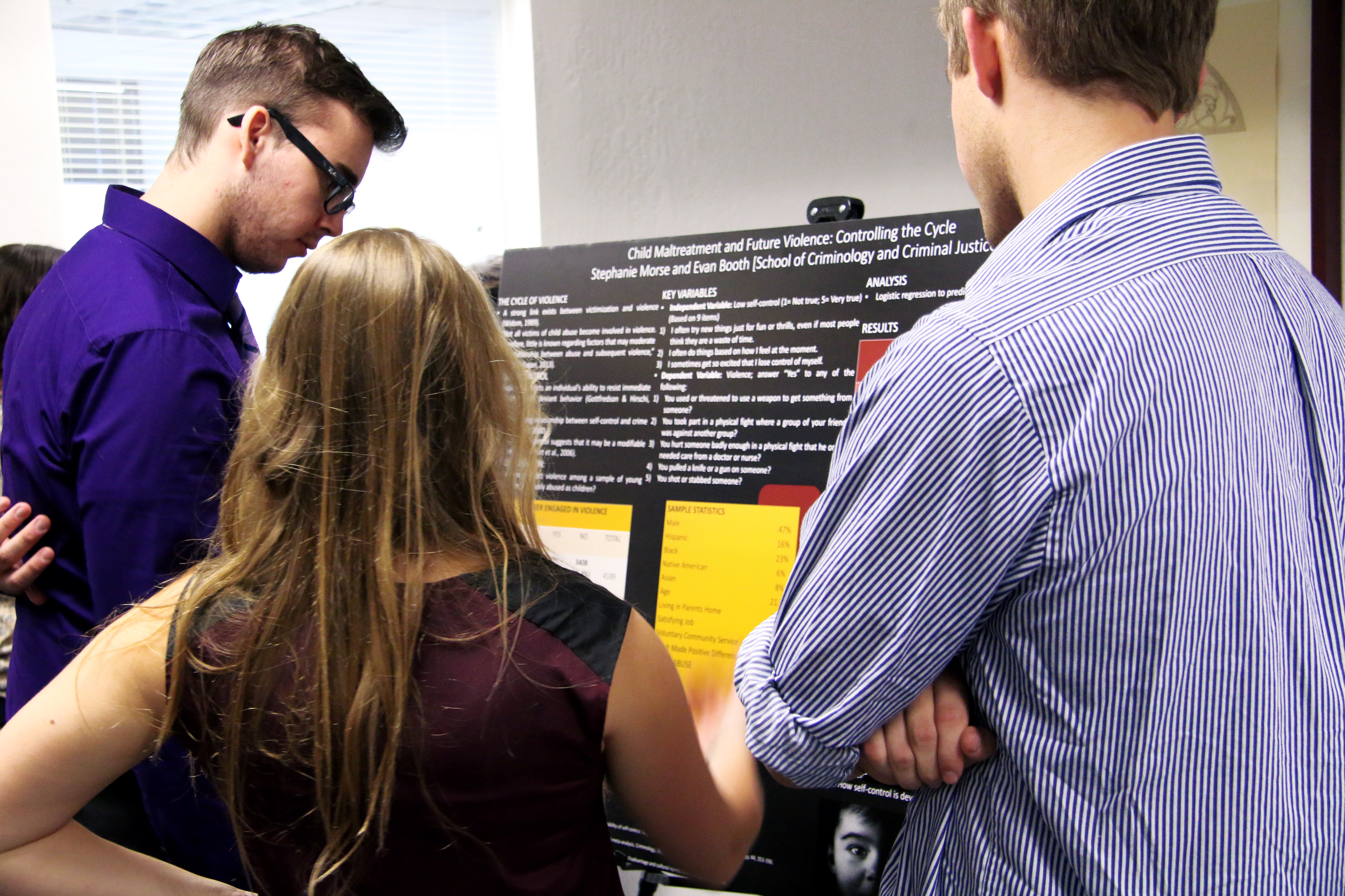 three college students looking at a research poster